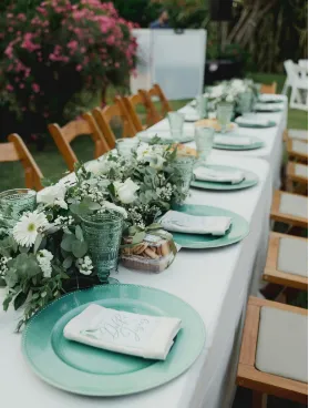 Mesa larga decorada para boda con vajilla verde y flores